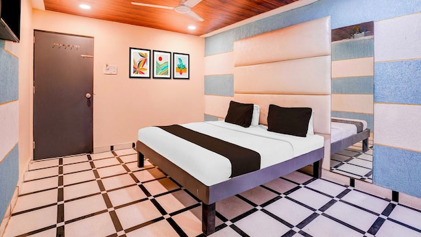 A hotel room with a bed, a ceiling fan, a door, and artwork on the wall. - Collection O Khoni Taloja Bypass (Mumbai)
