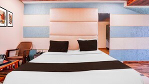 A hotel room with a large bed, a headboard, a chair, a table, and a telephone. - Collection O Khoni Taloja Bypass (Mumbai)