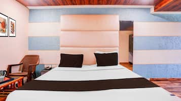 A hotel room with a large bed, a headboard, a chair, a table, and a telephone.