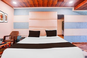 A hotel room with a large bed, a headboard, a chair, a table, and a telephone. - Collection O Khoni Taloja Bypass (Mumbai)