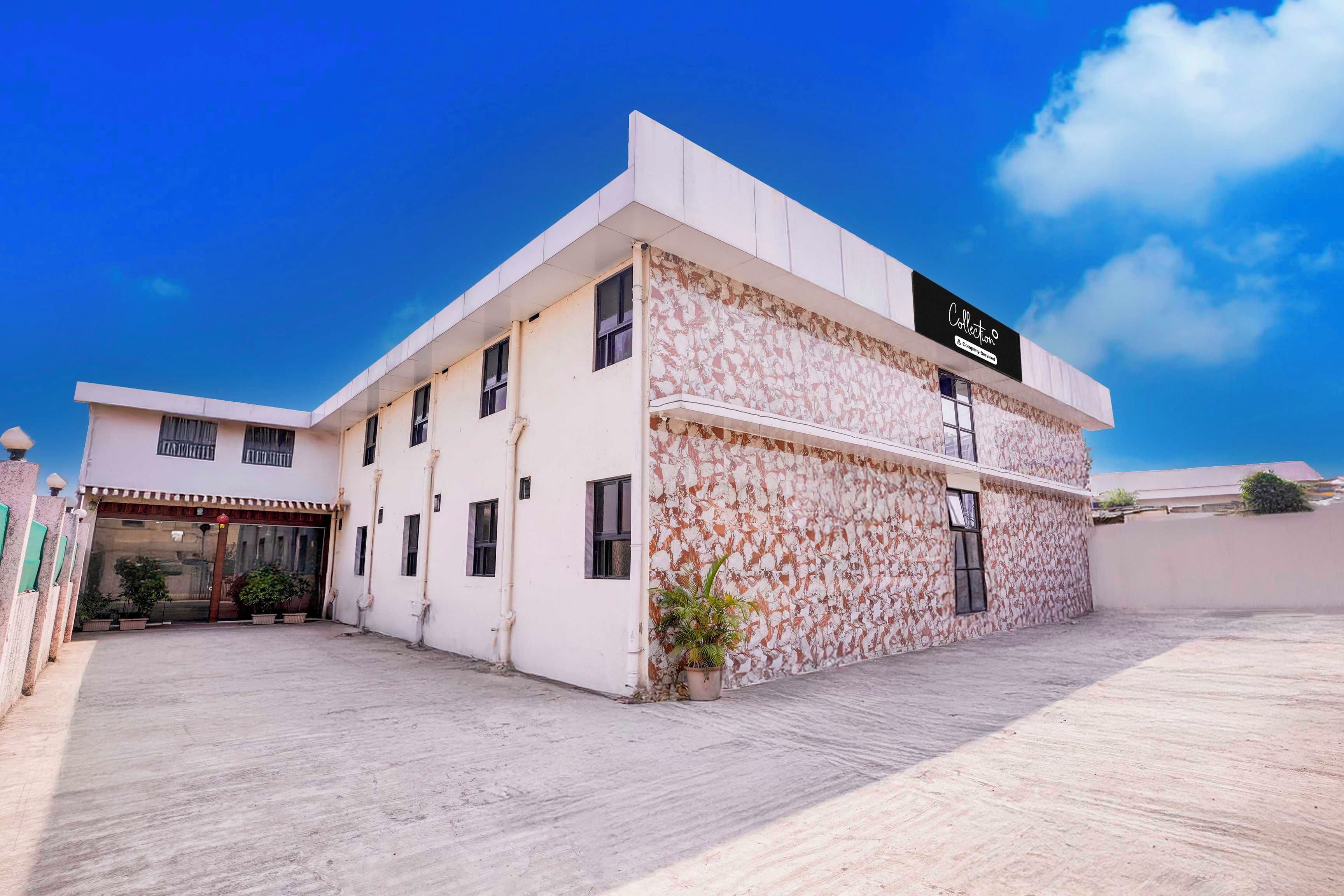A two-story building with a flat facade, a sign indicating a company service, and a gated entrance with potted plants.