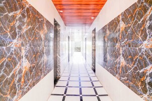 A corridor with marble walls and a checkered floor.