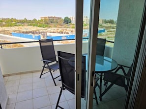Ein Balkon mit Glastür, zwei Stühlen und einem kleinen Tisch.