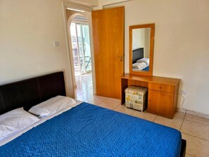 Un dormitorio con una cama, un aparador de madera, un espejo y una maleta.