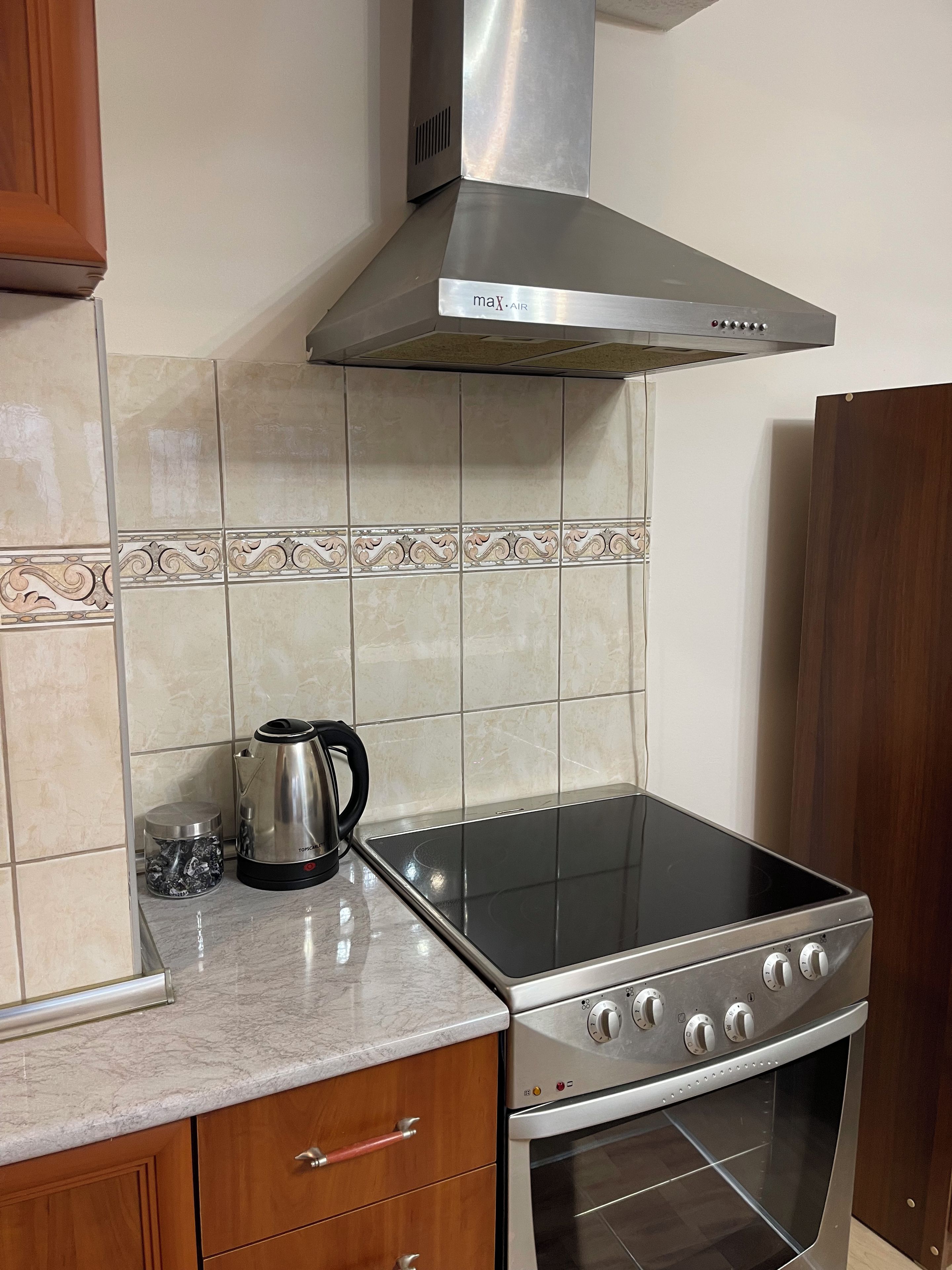 Cozinha com fogão, forno e coifa sobre o fogão.