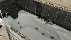 A bathroom with a white bathtub, a toilet, and a washing machine. - Central Charm Residence Kumanovo (Kumanovo)