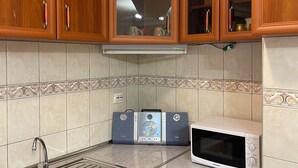 A kitchen with wooden cabinets, a microwave, a dishwasher, and a sink. - Central Charm Residence Kumanovo (Kumanovo)