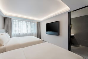 Et moderne hotelværelse med en seng, et fjernsyn ophængt på væggen og et badeværelse med mørke fliser.