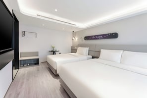 Et moderne hotelværelse med to senge, et siddeområde, et lille bord med en plante og et skilt monteret på væggen.