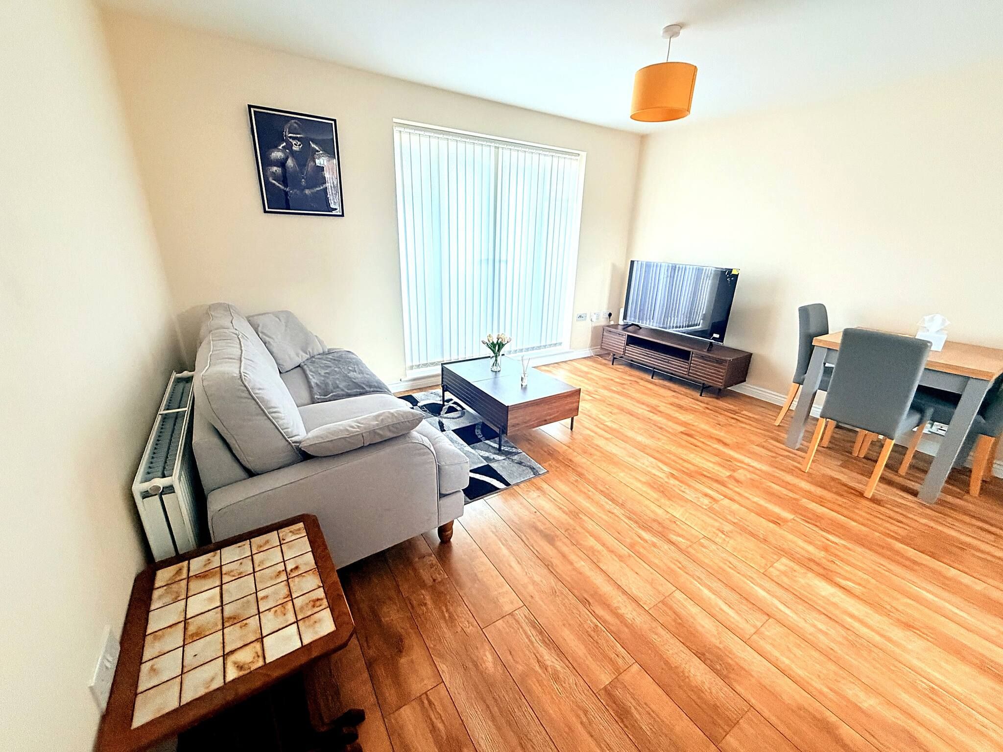A living room with a sofa, coffee table, TV stand, and a dining area with chairs.