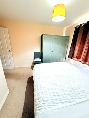 Une chambre à coucher avec un lit, une armoire, une table de chevet et une lampe.