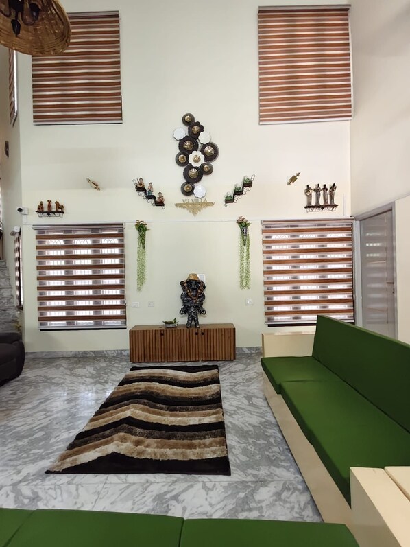 Una sala de estar moderna con un sofá verde, un tapete estampado y decoración en la pared.
