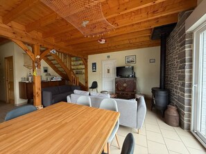 Ein gemütliches Interieur mit einem Holzesstisch, grauen Sofas, einer Treppe und einer Steinwand.