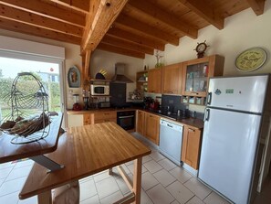 Eine Küche mit Holzschränken, einem Edelstahlkühlschrank und einem Holzessttisch.