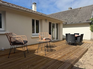 Una terraza de madera con mobiliario exterior, incluyendo sillas y una mesa.
