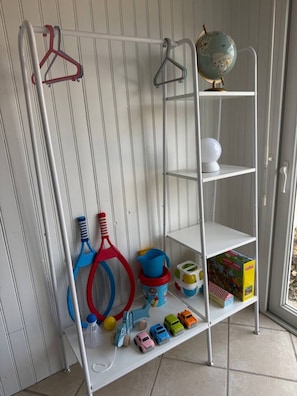 Uma estante metálica branca com vários compartimentos, alguns contendo brinquedos e um globo.