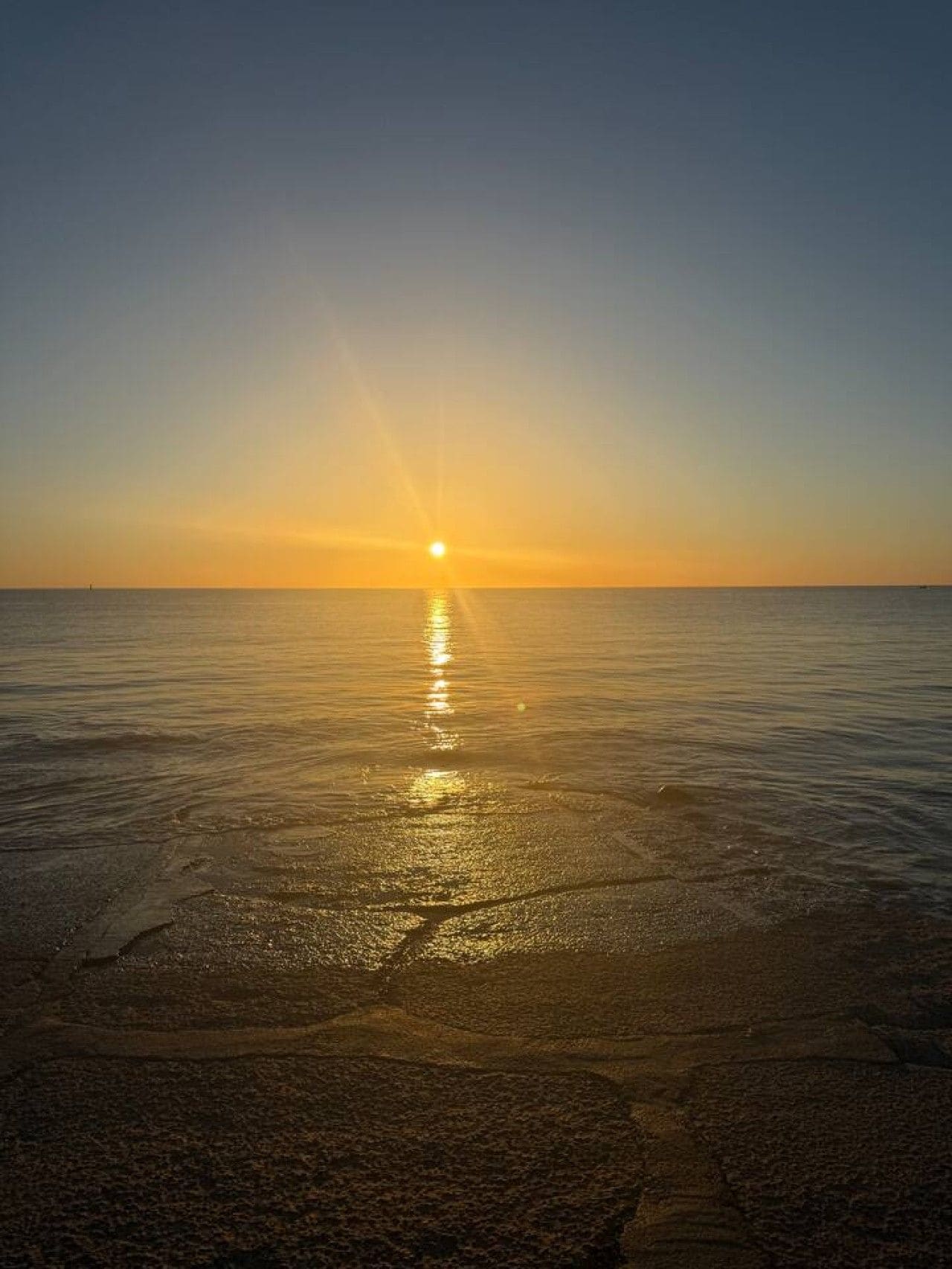 Ein Sonnenuntergang über einem ruhigen Meer mit klarem Horizont.
