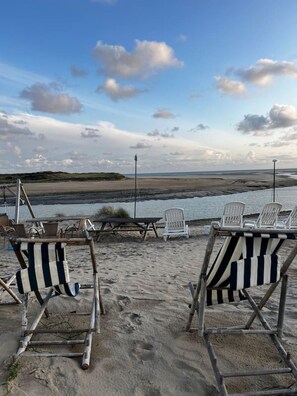Beach chairs and a picnic table on a sandy beach with a view of the ocean and distant hills. - Contemporary villa near the beaches of the Cotentin Peninsula (Saint-Germain-sur-Ay)