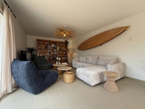 Ein Wohnzimmer mit einer Couch, einem blauen Sessel, einem Couchtisch und einem Bücherregal.