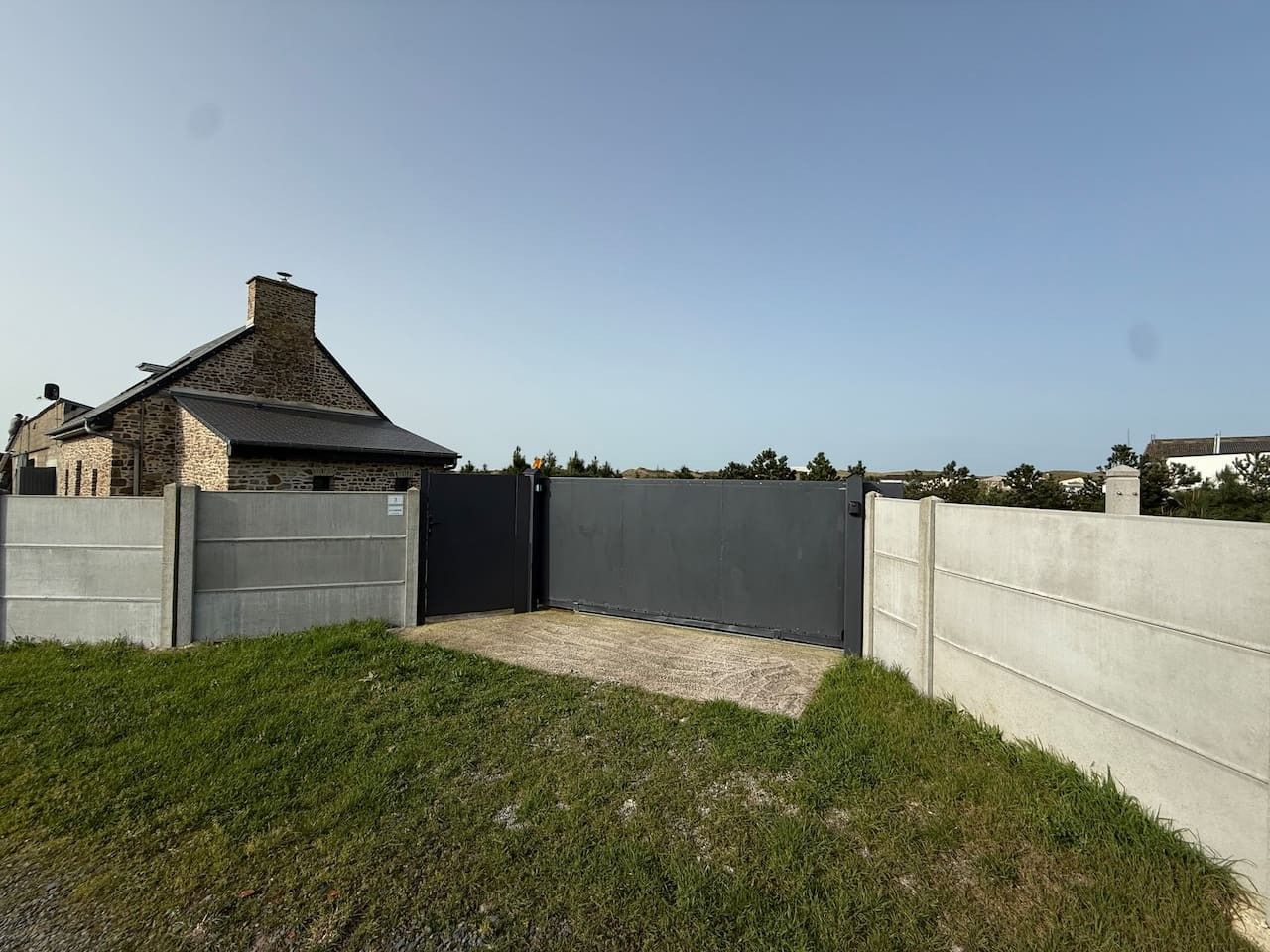 Ein von einer Mauer und einem Tor umgebenes Areal mit einem Steinhaus.