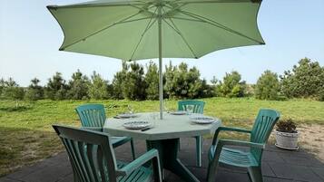 An outdoor patio with a round table, four chairs, and a large umbrella.