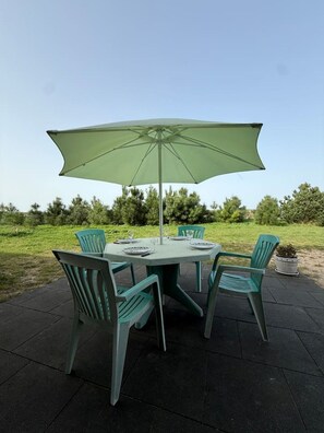 An outdoor patio with a round table, four chairs, and a large umbrella. - La Bergerie Lodge, 200 meters from the sea (Pirou)