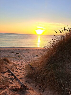 A beach scene with a sunset, sand, and sparse vegetation. - La Bergerie Lodge, 200 meters from the sea (Pirou)