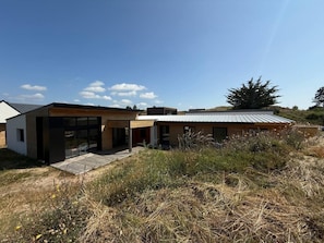 Uma casa moderna com telhado plano, janelas amplas e um deck de madeira.