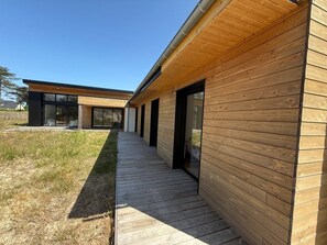 Ein modernes Gebäude mit Holzfassade und einem überdachten Zugang zu einem Glas Eingang.
