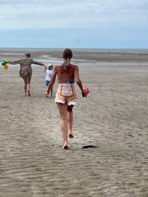Uma praia arenosa com pessoas caminhando.