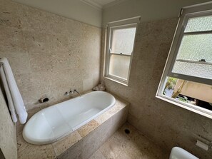 Ein Badezimmer mit Badewanne, Fenster und Toilette.