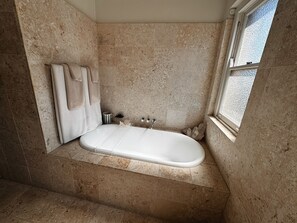 Une salle de bain avec une baignoire sur pieds, un porte-serviettes et une fenêtre.