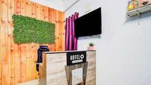 A reception desk with a 'HOTEL' sign, a green wall with foliage, and a flat-screen TV mounted on the wall. - Hotel O Chandanagar Formerly Nakshatra (Hyderabad)