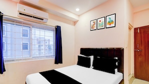 A hotel room with a bed, a window with curtains, an air conditioning unit, and three framed pictures on the wall. - Hotel O Chandanagar Formerly Nakshatra (Hyderabad)
