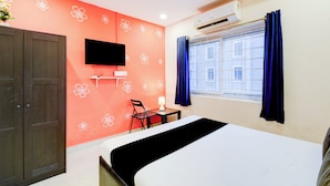 A hotel room with a bed, a desk, a chair, an air conditioning unit, and a window with curtains. - Hotel O Chandanagar Formerly Nakshatra (Hyderabad)