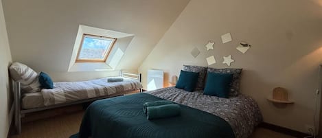 Un dormitorio con una cama individual, una litera, un tragaluz y arte decorativo en la pared.
