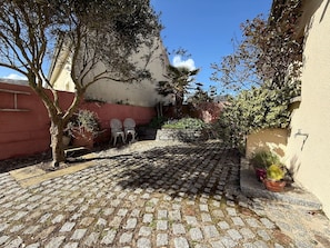 A paved courtyard with a tree, potted plants, and two chairs. - Family home near the beach, 5 bedrooms, pool table, garden (Bretteville-sur-Ay)
