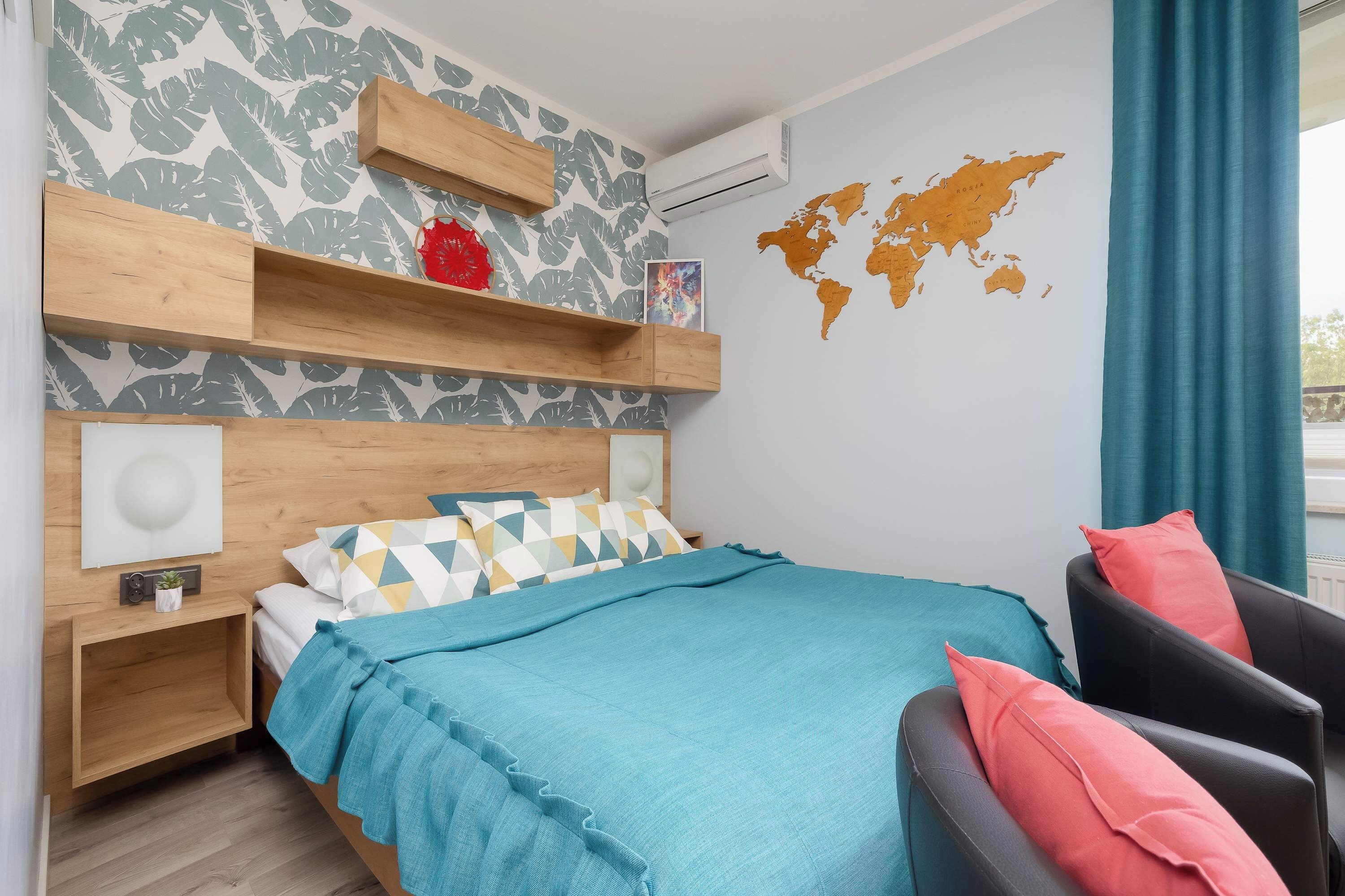 Una camera da letto moderna con un letto, una sedia, una mappa del mondo appesa al muro e uno scaffale in legno.