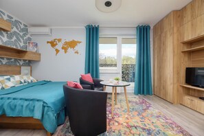 A modern bedroom with a bed, a chair, a small table, and a TV.