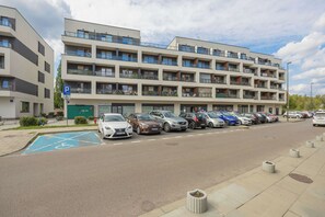 A multi-story parking garage with a row of cars parked on the street in front.