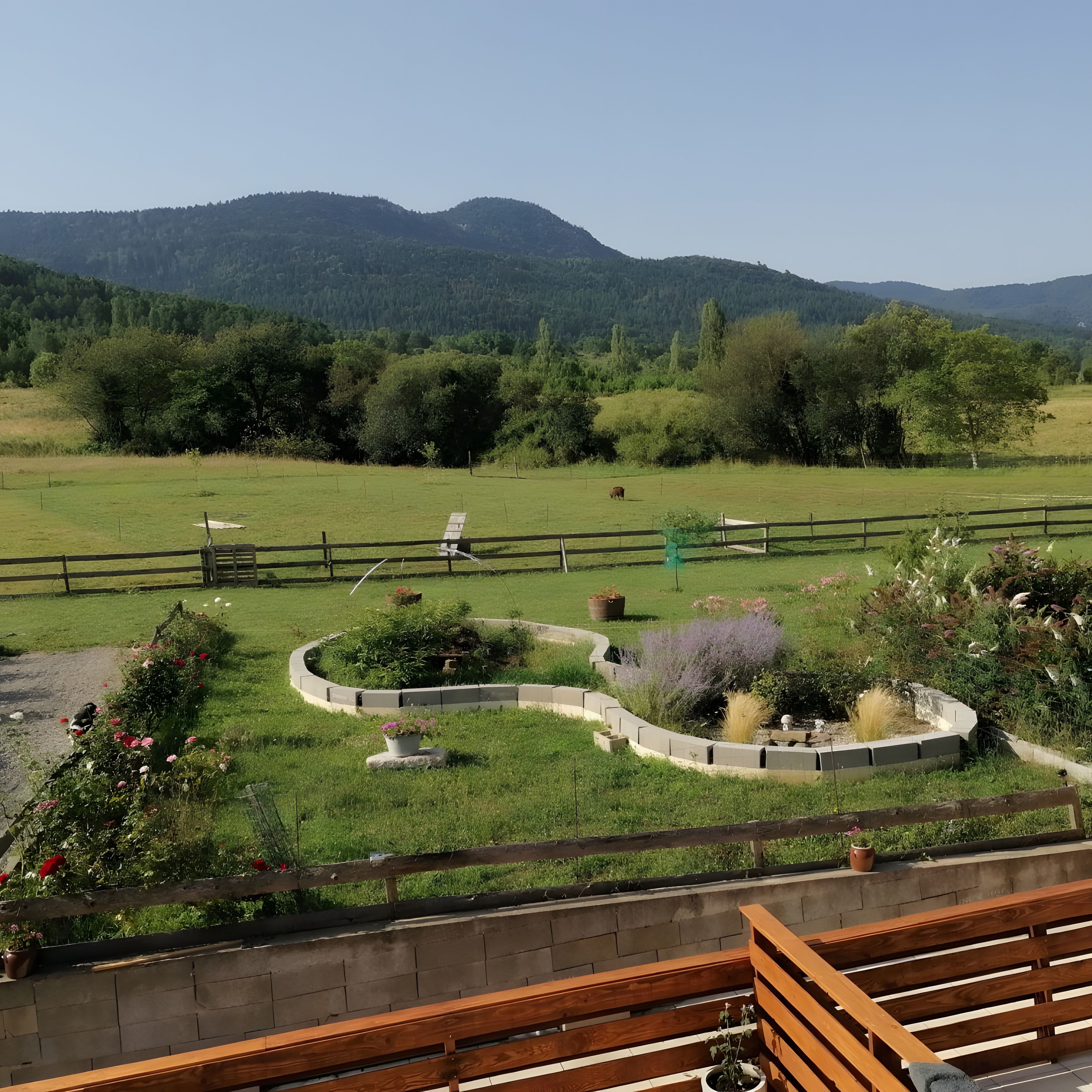 Un jardin aménagé avec un banc en bois, un parterre de fleurs circulaire et une vue sur une chaîne de montagnes.