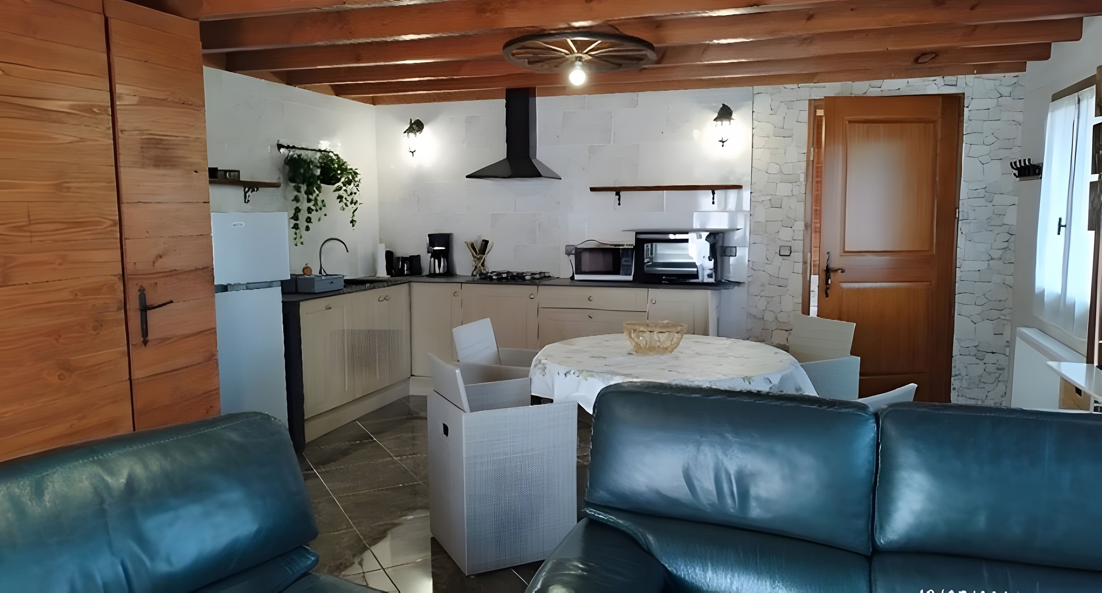 Una cocina compacta con electrodomésticos modernos, un comedor con mesa y sillas, y un rincón de estar con un sofá.