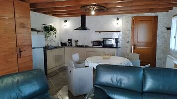 Una cocina compacta con electrodomésticos modernos, un comedor con mesa y sillas, y un rincón de estar con un sofá.