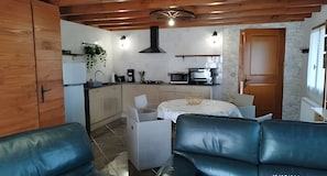 A compact kitchen with modern appliances, a dining area with a table and chairs, and a seating area with a sofa.