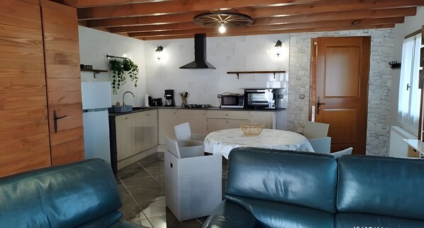 Una cocina compacta con electrodomésticos modernos, un comedor con mesa y sillas, y un rincón de estar con un sofá.