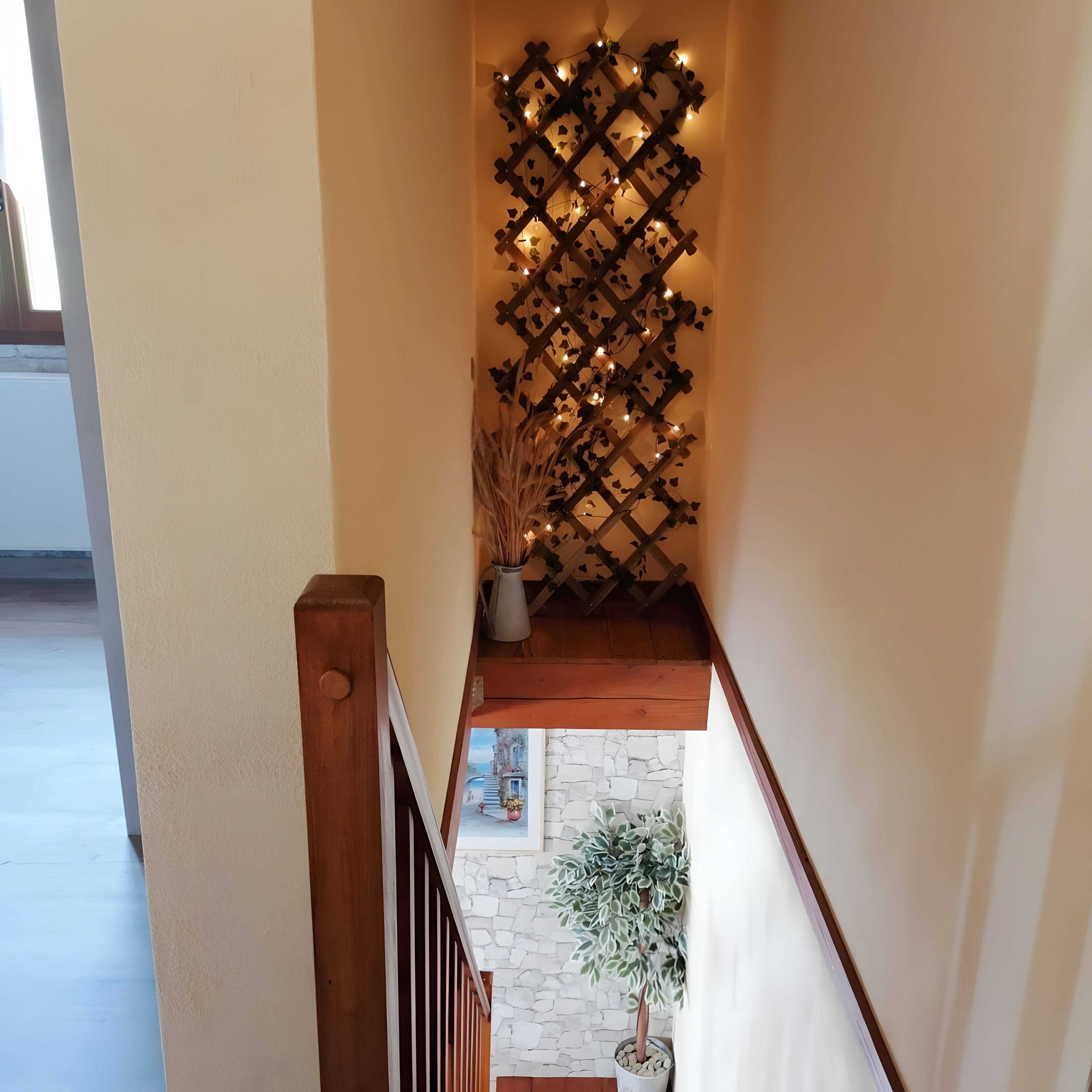 Escada com corrimão de madeira e luminária na parede com pequenas lâmpadas.