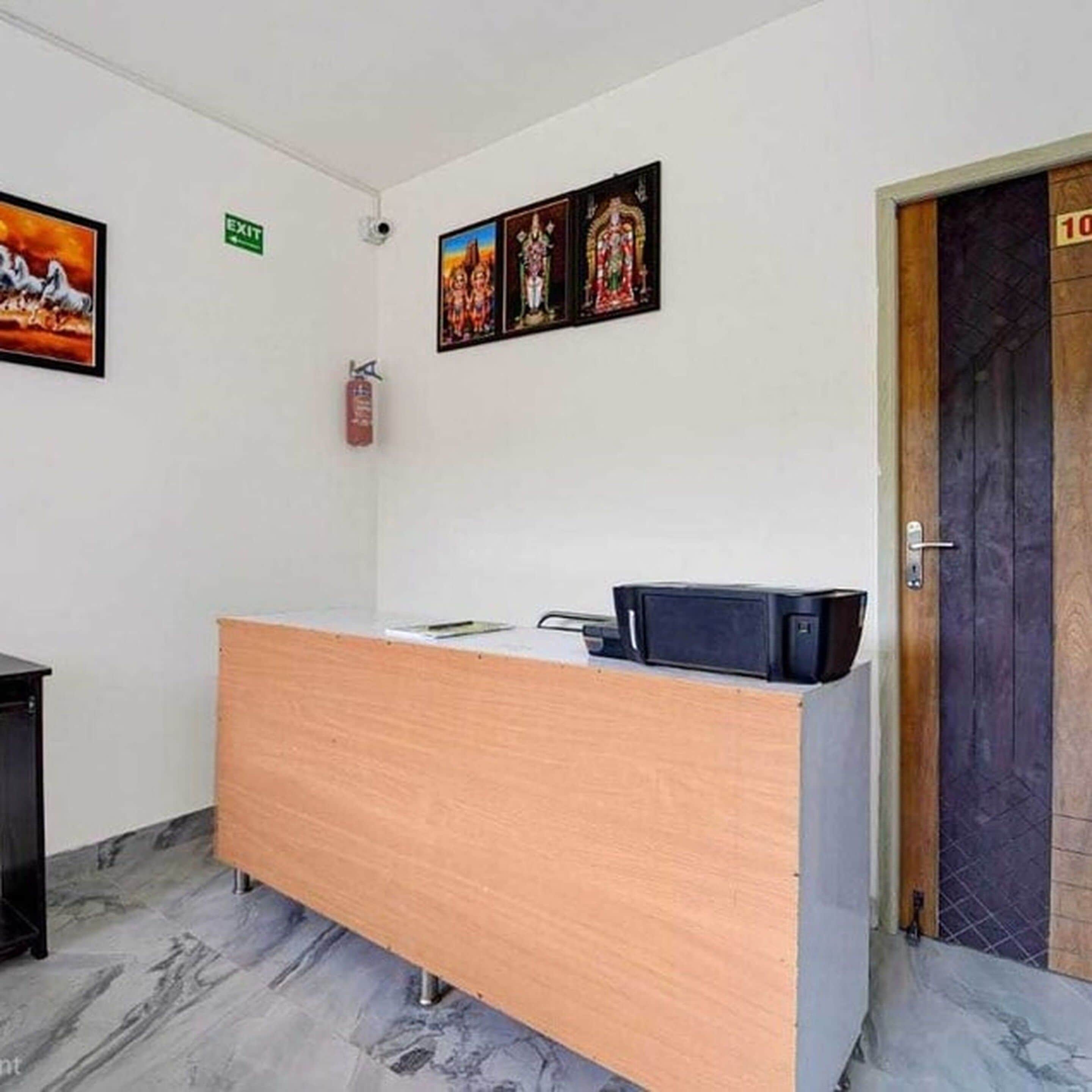 Un mostrador de recepción con una computadora, un extintor y una puerta marcada con el número 10.