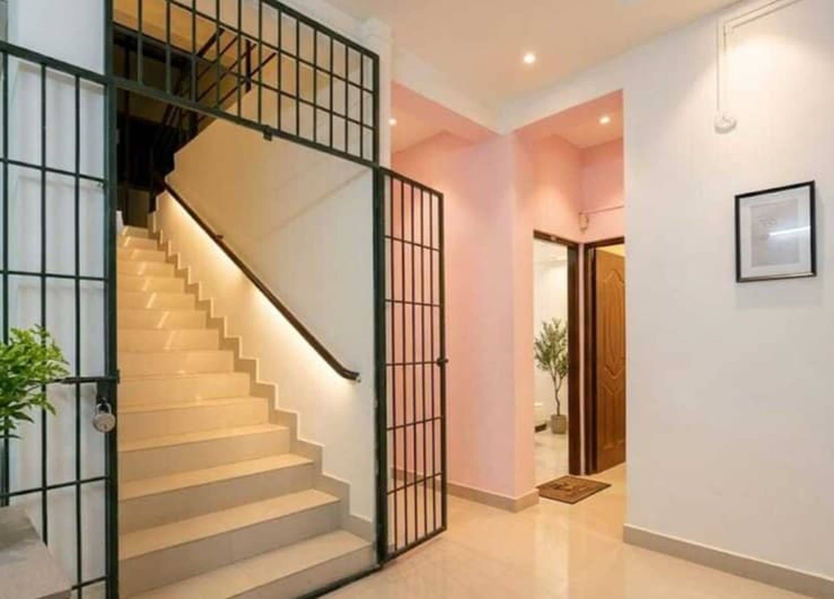 A staircase with a metal railing leading to a landing, a door with a glass panel, and a framed picture on the wall.