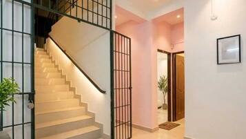 A staircase with a metal railing leading to a landing, a door with a glass panel, and a framed picture on the wall.