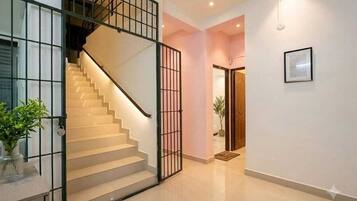 Una escalera con barandilla de metal que lleva a una plataforma, una planta en maceta y un cuadro en la pared.